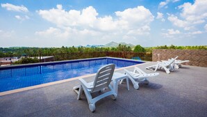 Una piscina con sillones de descanso y vistas al paisaje.