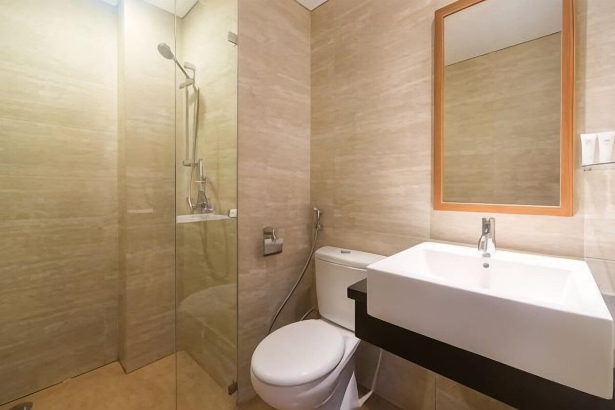 Une salle de bain avec une douche à parois de verre, des toilettes et un lavabo avec un miroir au-dessus.
