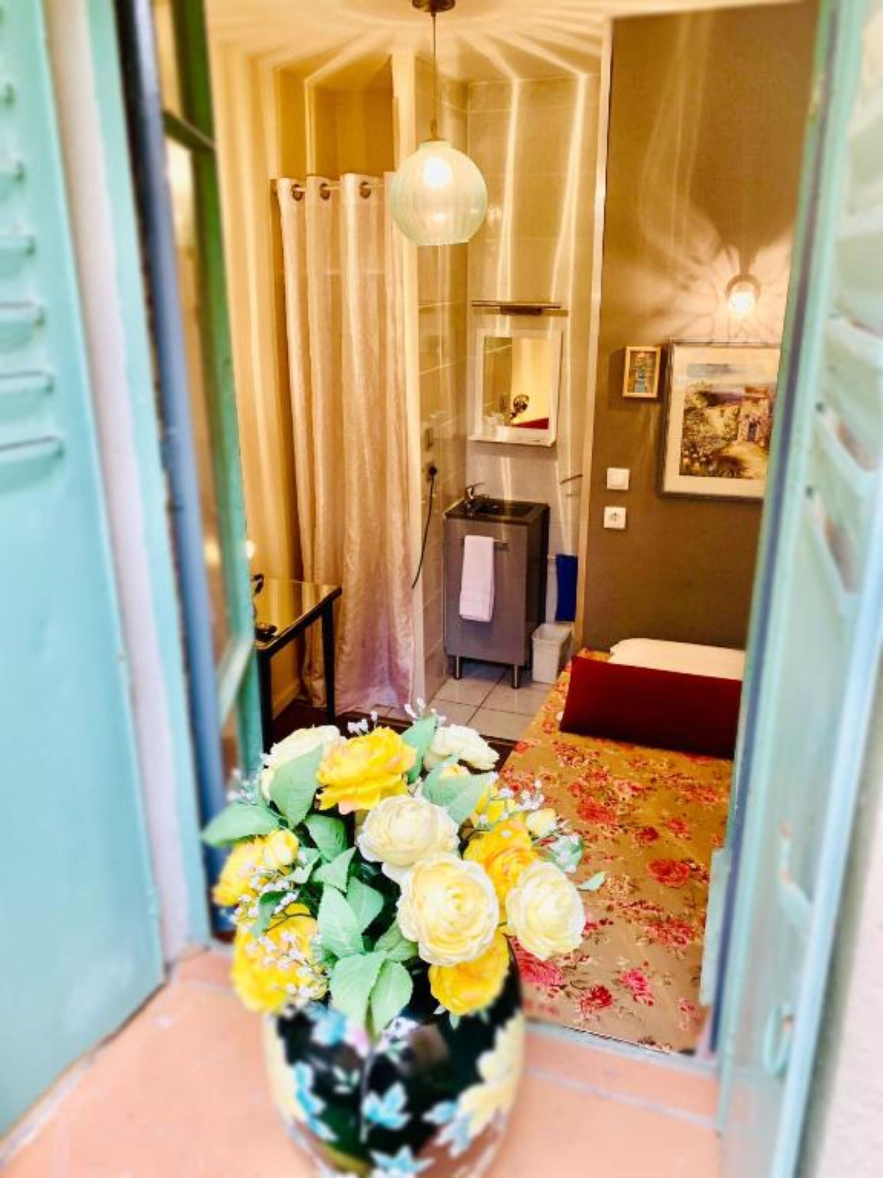 Un pasillo con un arreglo floral, una zona de ducha y una cama con cubrecama floral.