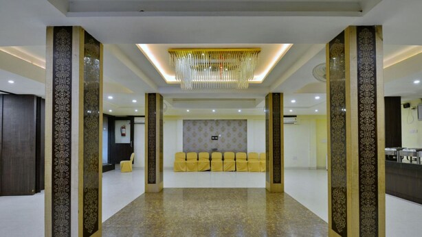 A spacious lobby with a central seating area, decorative columns, and a modern chandelier.