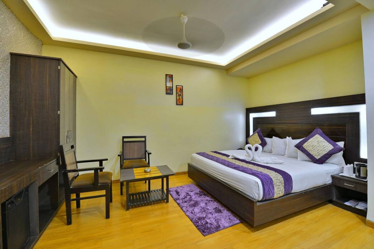 Ein Hotelzimmer mit Bett, Schreibtisch, Stuhl, Kleiderschrank und Deckenventilator.