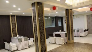 A banquet hall with tables set for events, featuring high-backed chairs and a polished floor.
