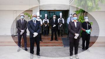 A group of people in formal attire standing in front of a building with a closed shutter door.
