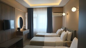 Une chambre d’hôtel avec deux lits, une télévision, un miroir et un bureau.