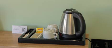 Una estación de café con una tetera, tazas y una bandeja.
