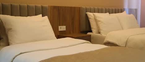 A hotel room with two beds, wooden headboard, and a nightstand with a lamp.