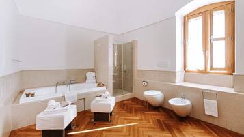 Ein modernes Badezimmer mit einer großen Badewanne, einer Dusche, einer Toilette und einem Waschbecken.
