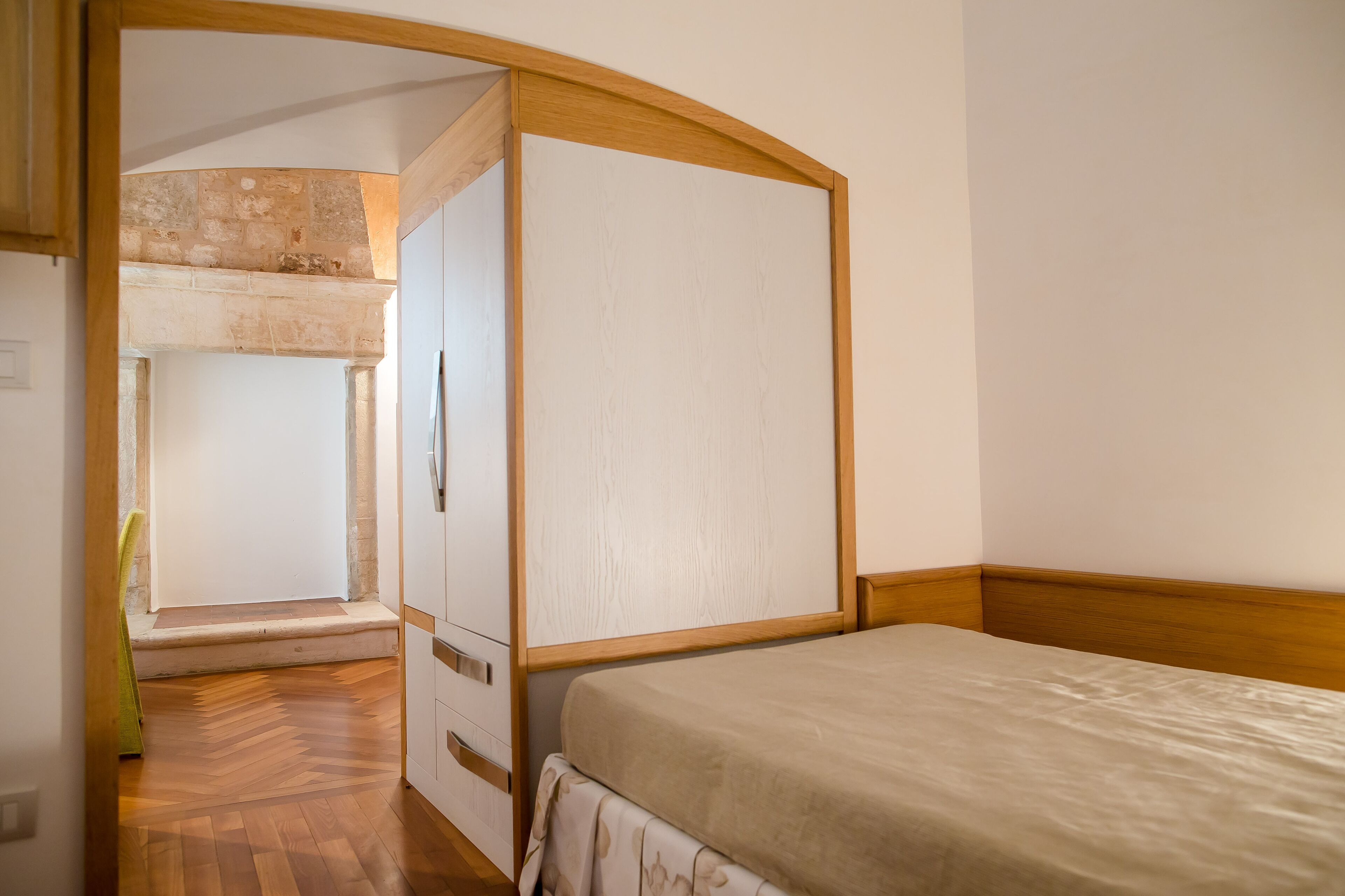 A bedroom with a wooden bed frame, a white headboard, and a wooden floor.