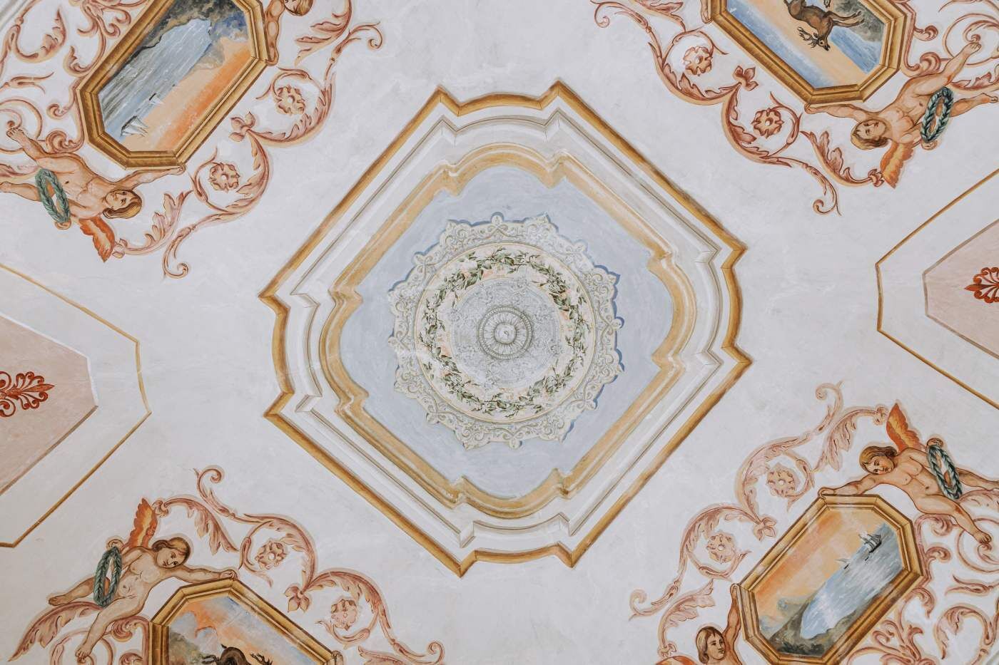 A ceiling with ornate, symmetrical patterns and classical artwork.