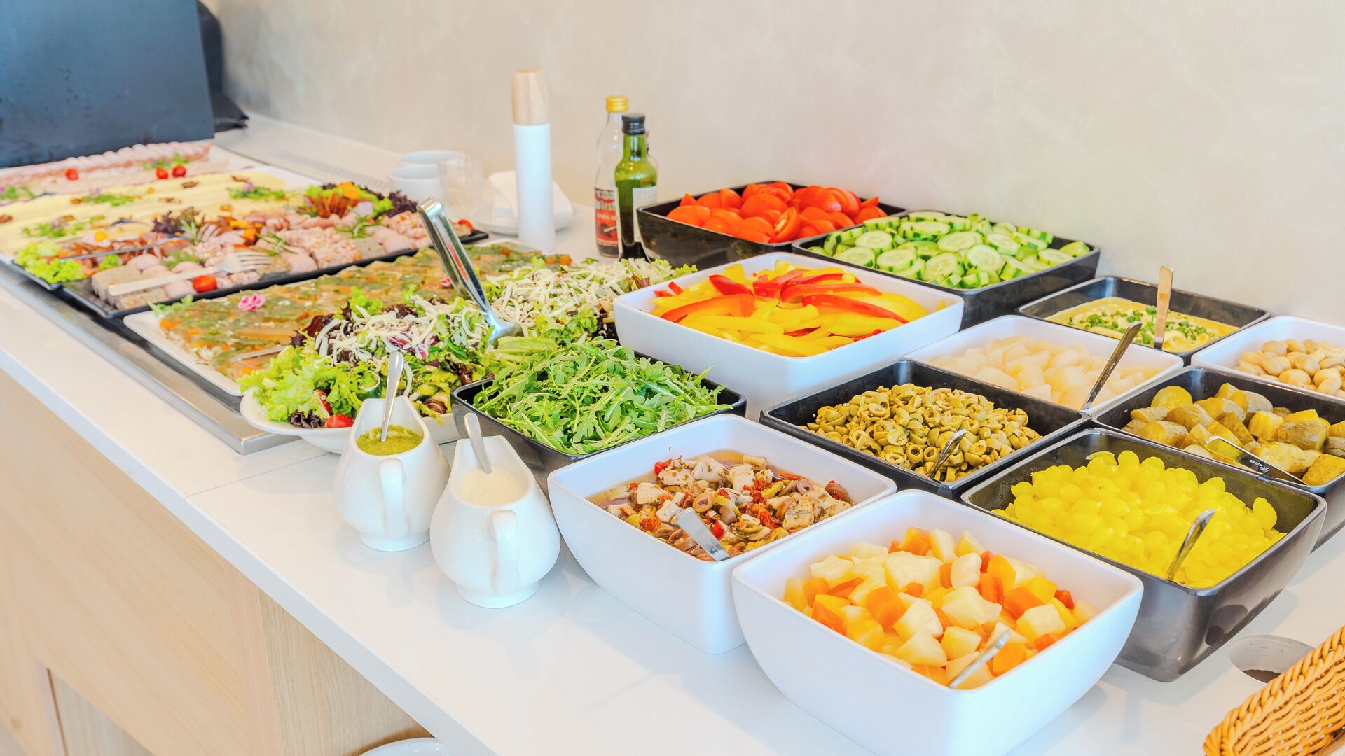 Een buffet met diverse gerechten, zoals salades, fruit en vlees.