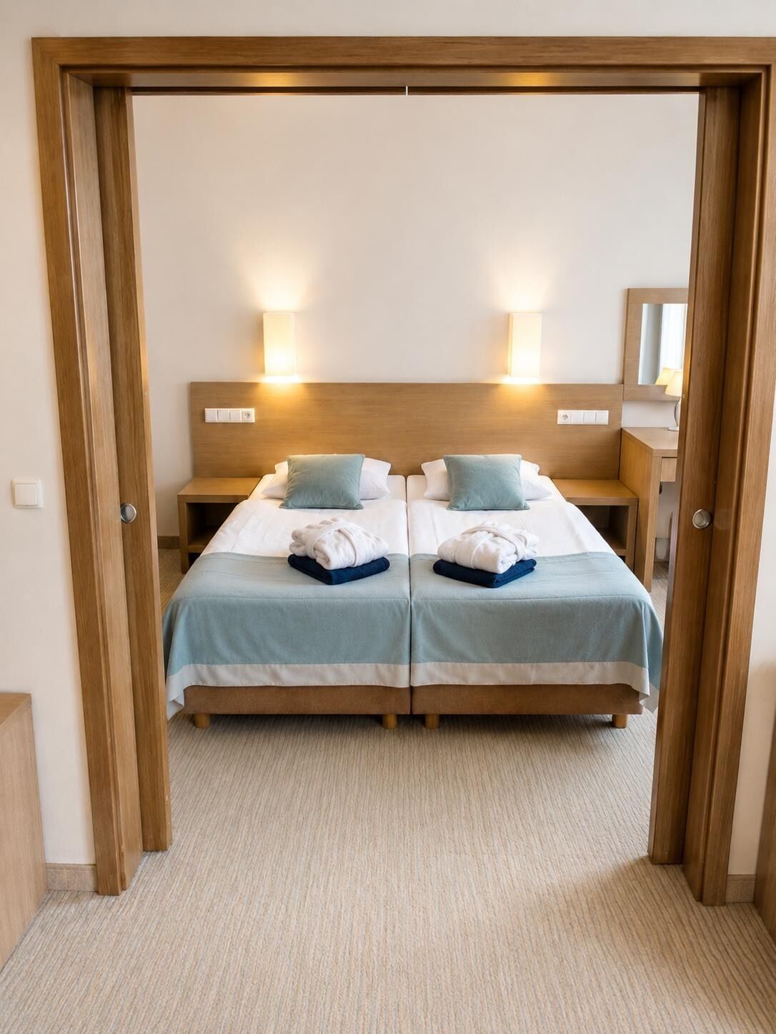 A double room with two beds, each with a headboard, bedside tables, and lamps.