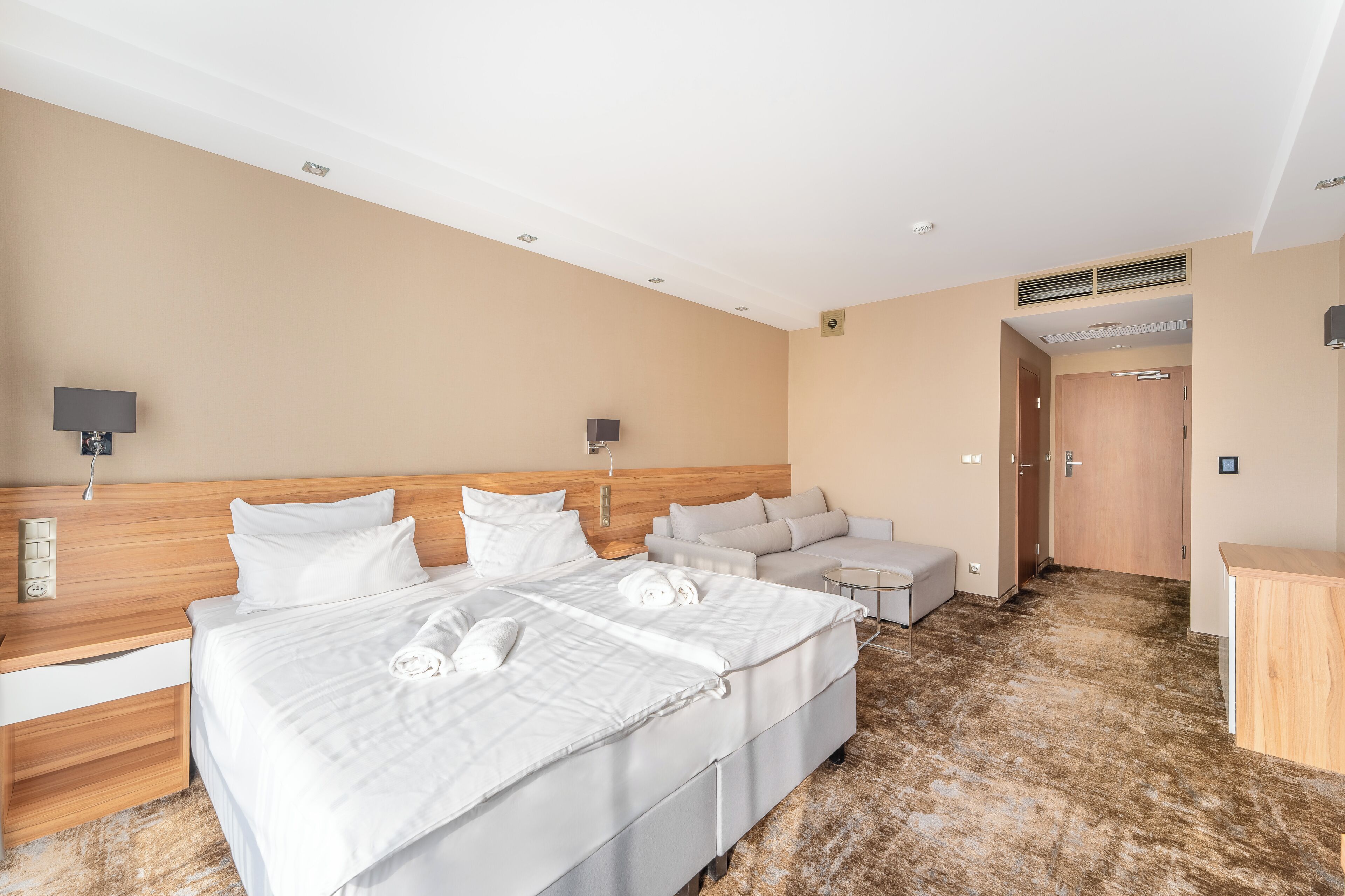 Quarto de hotel com uma cama grande, sofá, escrivaninha e armário.