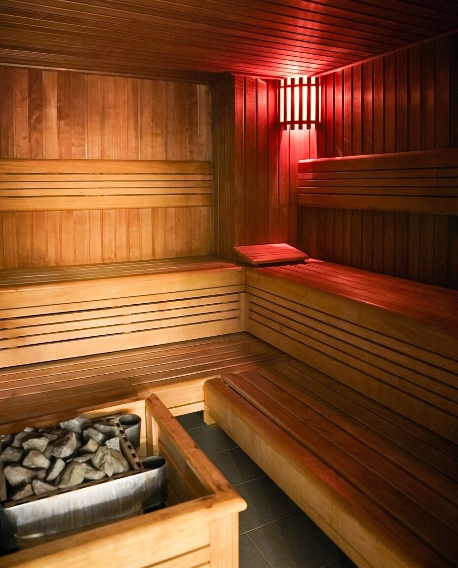 Un sauna avec des bancs en bois et un récipient en métal rempli de pierres.