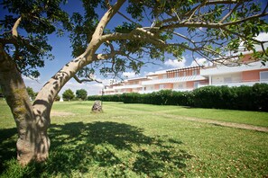 A building with a modern architectural style, a well-maintained lawn, and a large tree in the foreground.