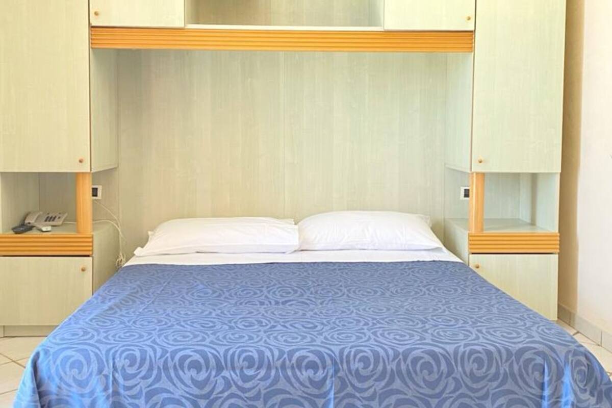 Une chambre avec un lit superposé, une armoire et une table de chevet.