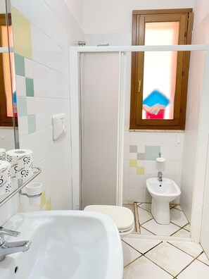 A bathroom with a white sink, a bidet, and a shower enclosure.