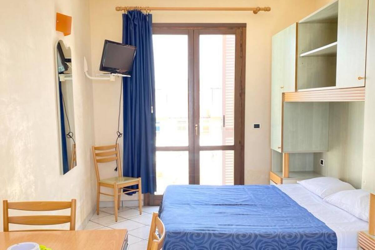 Une chambre d’hôtel équipée d’un lit, d’un bureau, d’une chaise, d’une télévision et d’une armoire.