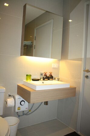 A modern bathroom with a white sink, mirror, and toilet.