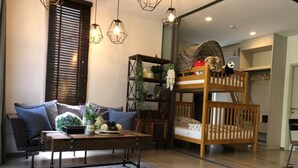 Una sala de estar acogedora con un sofá, una mesita de centro, una litera y lámparas colgantes.