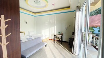 Una habitación de hotel con cama, un banco, una mesa con botellas y vistas al exterior.