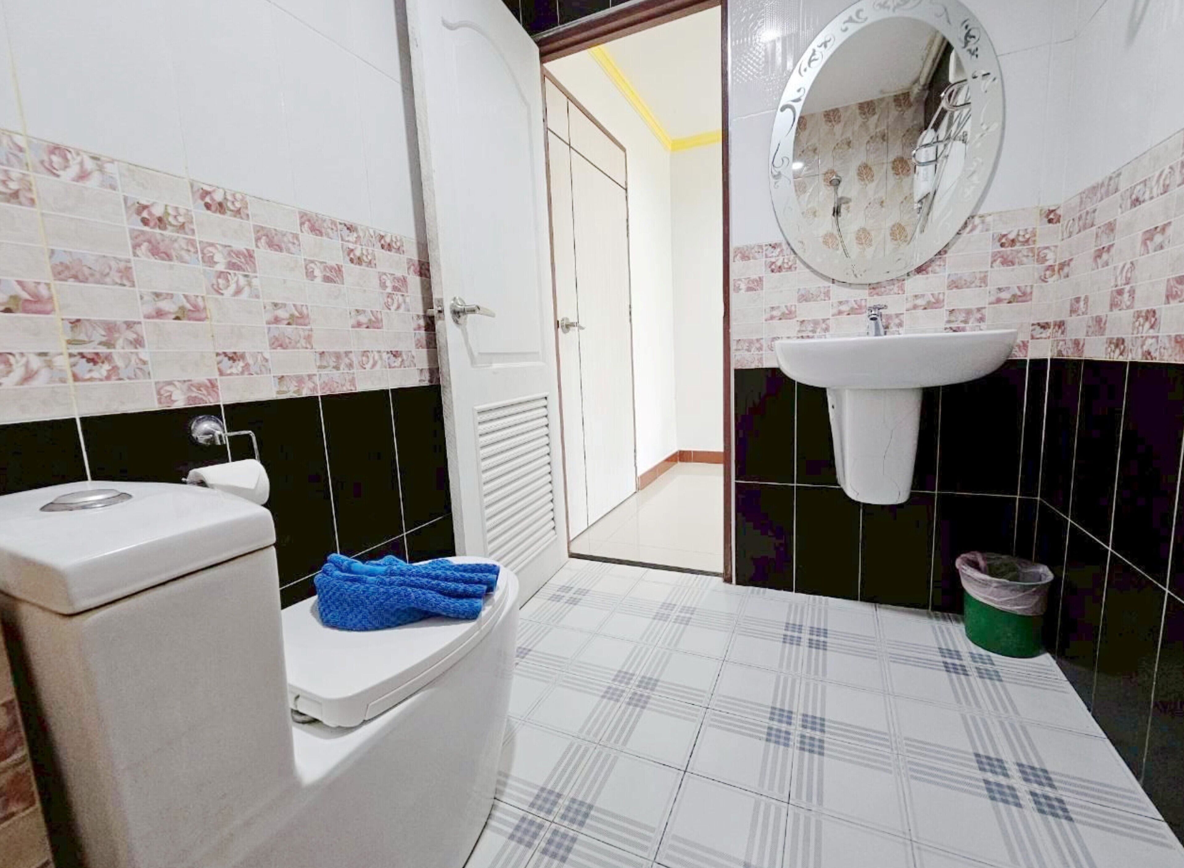 A bathroom with a toilet, a sink, a mirror, and patterned tiles.