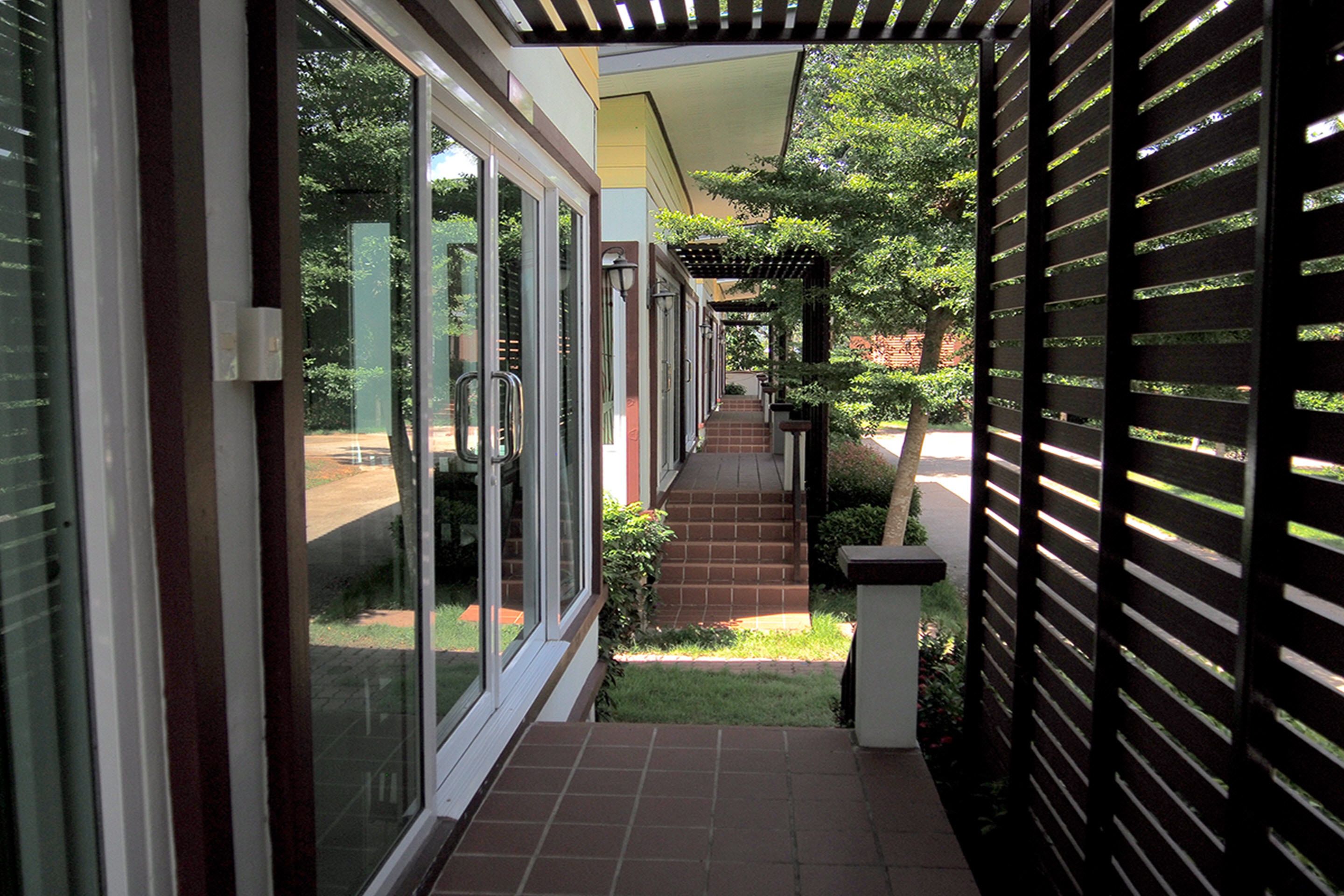 A covered outdoor corridor with glass doors leading to a garden area.