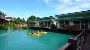 A pool area with kayaks, a wooden deck, and buildings with large windows. - Laketerrace Resort (La-ngu)