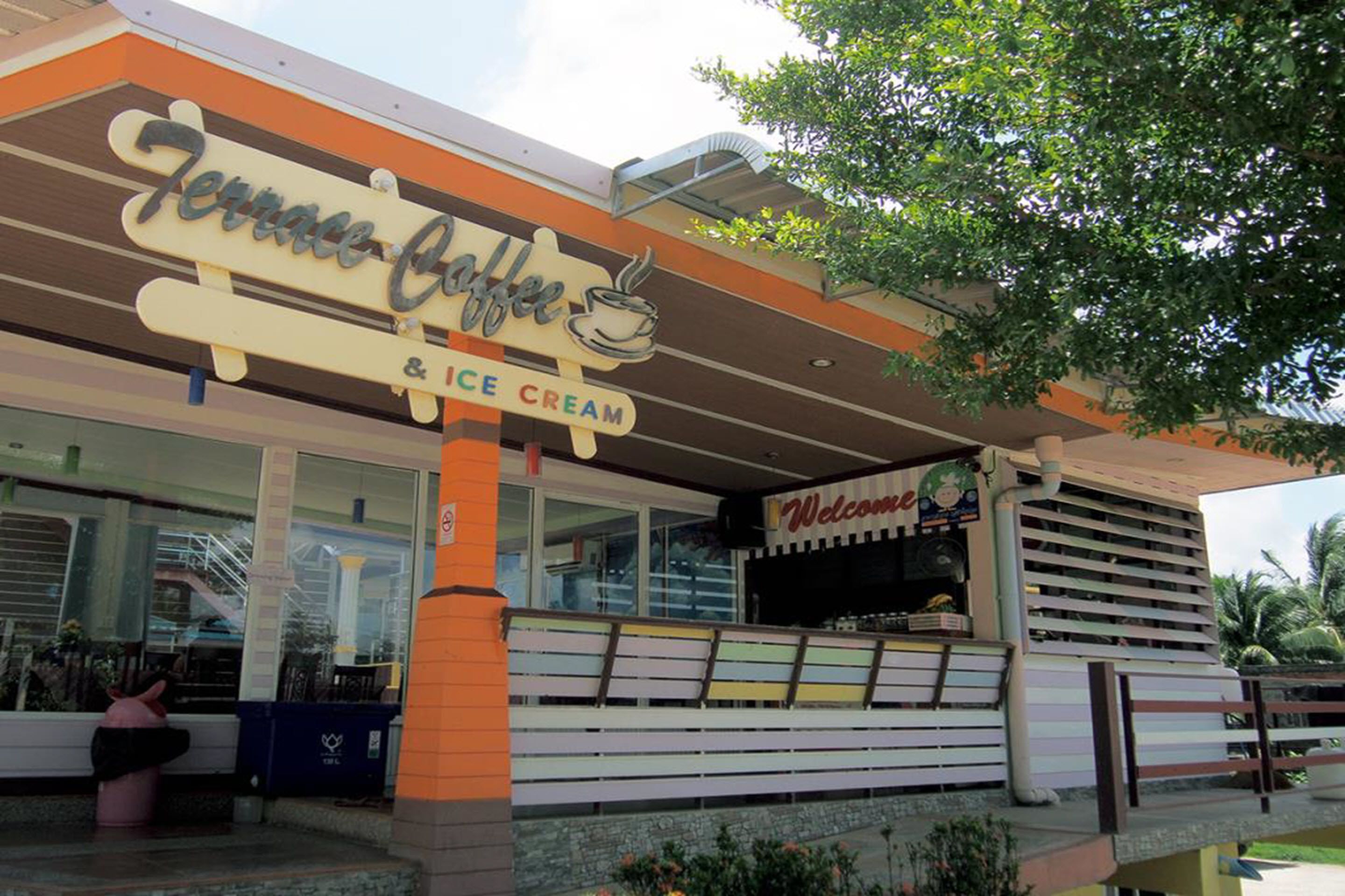 A restaurant named Terrace Coffee & Ice Cream with a 'Welcome' sign and a colorful bench outside.