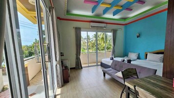 Una habitación con balcón, cama, sofá y mesa.