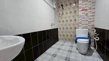 A bathroom with a white toilet, a white sink, and a shower area.