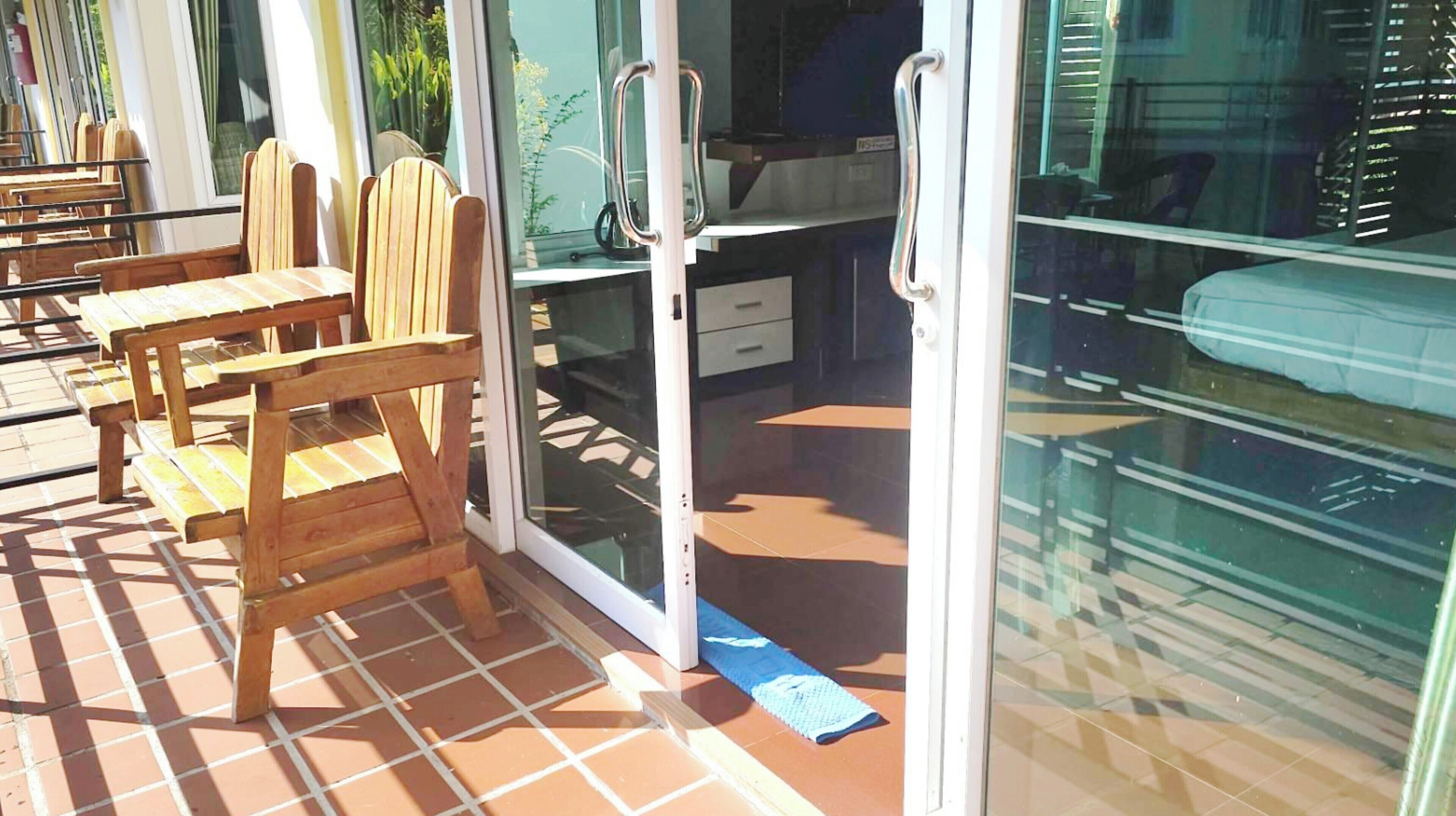 A room with a sliding glass door leading to a patio area with wooden chairs and a tiled floor.