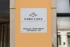 Señal para 'FARO COSY GUEST HOUSE' con un número de contacto para reservas.
