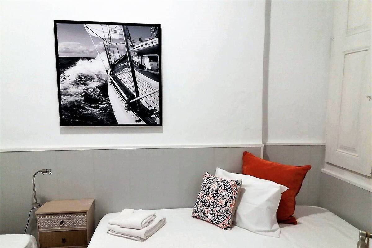 A hotel room with a bed, a nightstand, a wall-mounted picture, and a window.