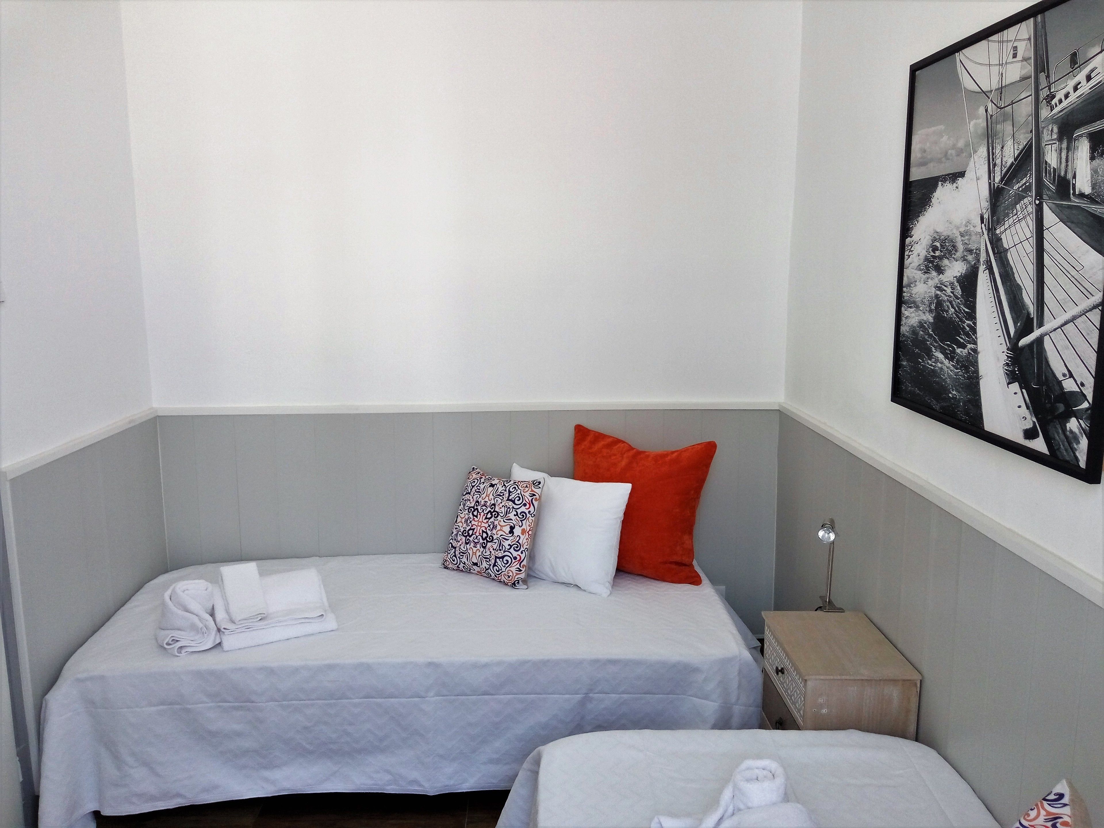 Una habitación de hotel con dos camas, una pared gris y un cuadro con un puente.