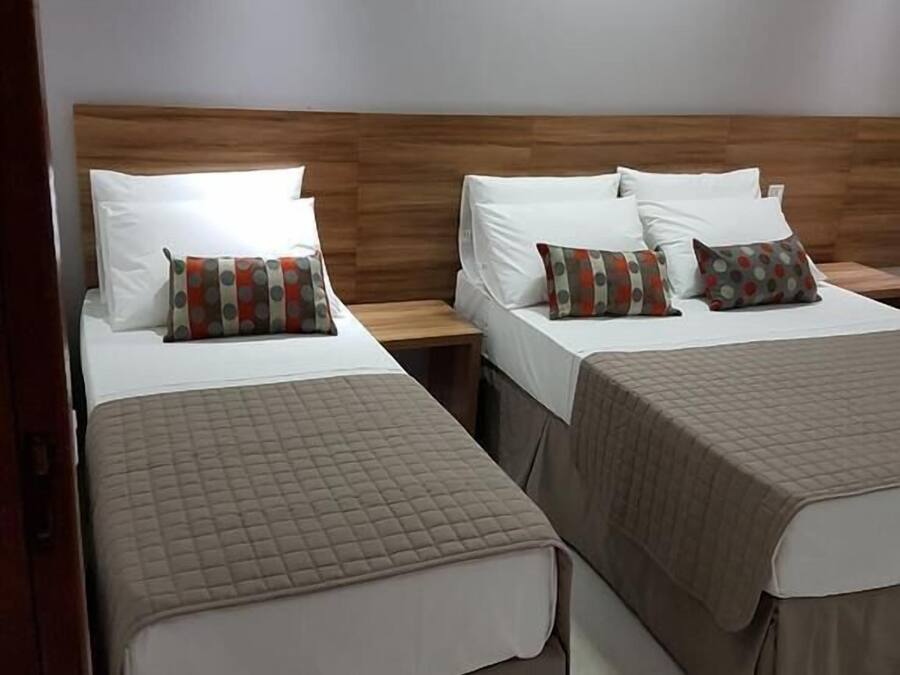 Een hotelkamer met twee bedden, elk voorzien van een houten hoofdeinde en witte beddengoed.