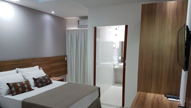 Una habitación de hotel con cama, mesita de noche y televisión.
