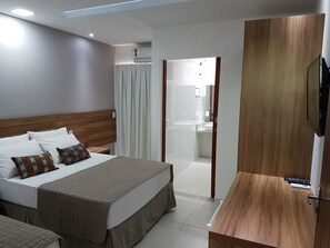 A hotel room with a bed, bedside table, and a TV.