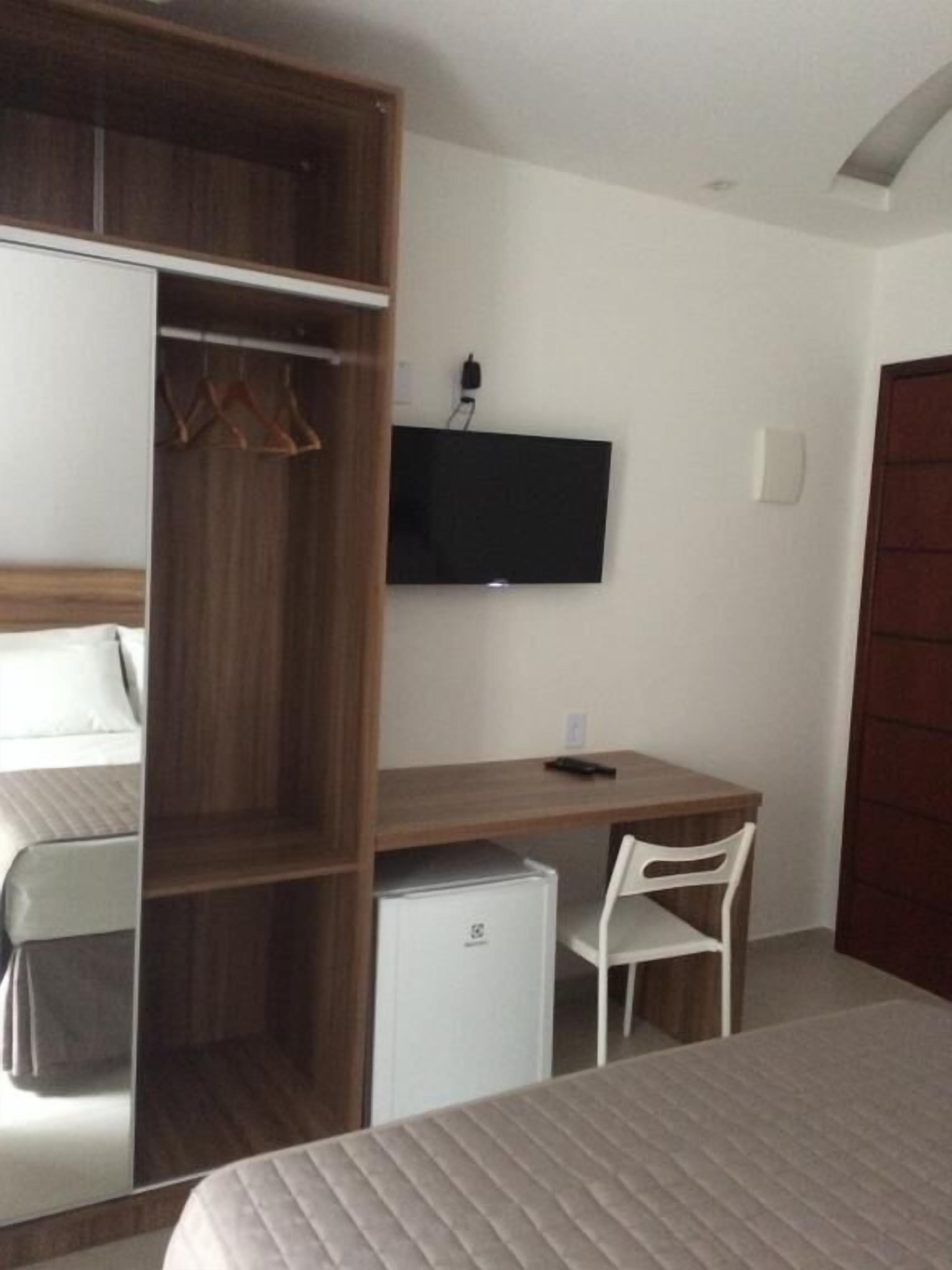 Una camera da letto con un letto, una scrivania, una sedia, un armadio e una televisione.