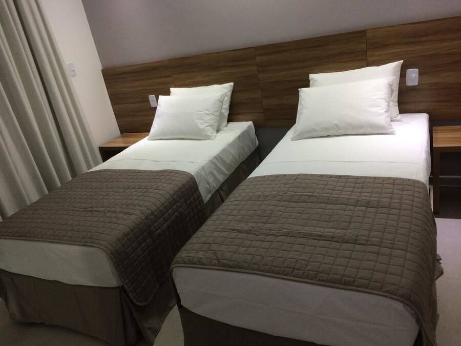 A hotel room with two beds, each with a wooden headboard and white bedding.