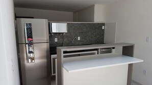 Una cocina compacta con refrigerador incorporado, microondas y una pequeña encimera.
