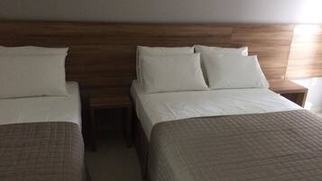 A hotel room with two beds, each with a wooden headboard and white bedding.