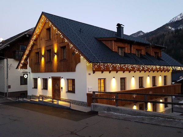 A wooden chalet with a steeply pitched roof, multiple windows, and a wooden balcony.