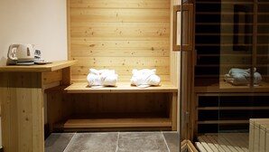 Una sauna de madera con bancos, toallas, una tetera y una mesita.