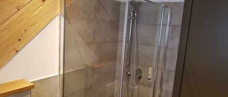 Una ducha con puerta de vidrio, techo de madera y pared de azulejos.