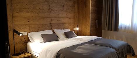 A wooden-paneled bedroom with a bed, bedside lamps, and a nightstand.