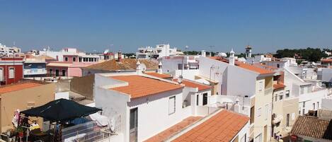 A residential area with white buildings, red-tiled roofs, and a clear blue sky.