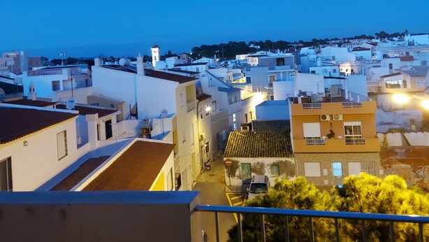 A balcony overlooking a coastal town at dusk.