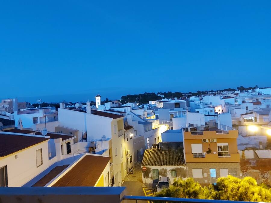 Un balcón con vistas a un pueblo costero al atardecer.