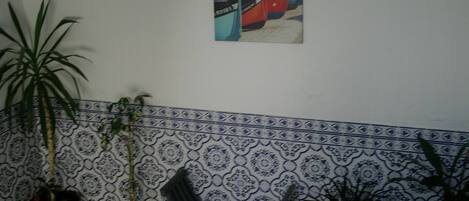 Una escalera con un muro decorado, plantas en macetas y un cuadro con una imagen de un autobús rojo.
