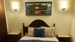 A neatly made bed with a blue quilt, two pillows, and three towels arranged in a fan shape.